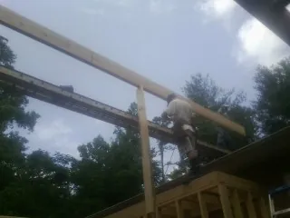 Carpenter setting a ridge beam over a new addition frame — Ice Dam Removal by Roofing Brothers in Sour Lake