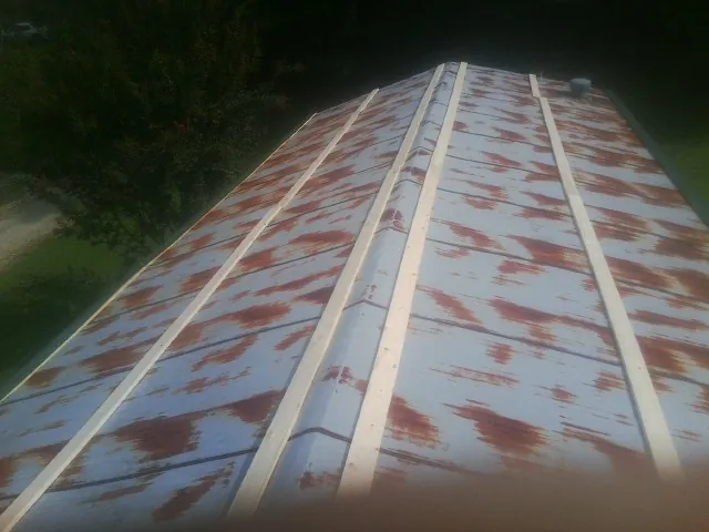 Rusted metal roof panels with new wood purlins before replacement — Storm Damage Roof Repair in Sour Lake by Roofing Brothers