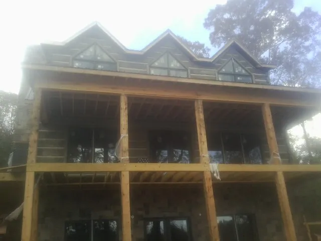 Dormers and porch framing on a large log home under construction — Roof Coating work by our crew in Sour Lake